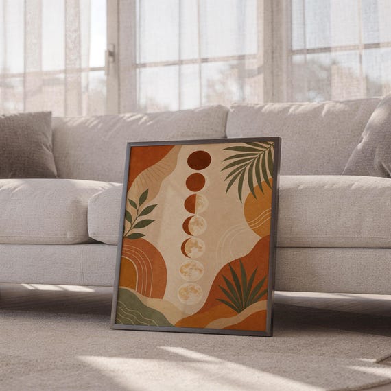 Boho moon phases art print leaning against a white sofa in a bright living room with sheer curtains.