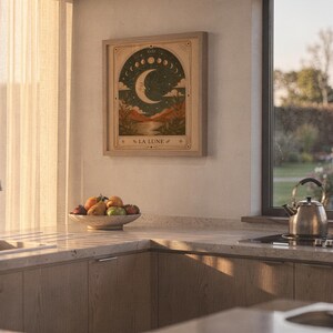Earthy terracotta moon art poster framed on kitchen wall illuminated by warm sunset light.