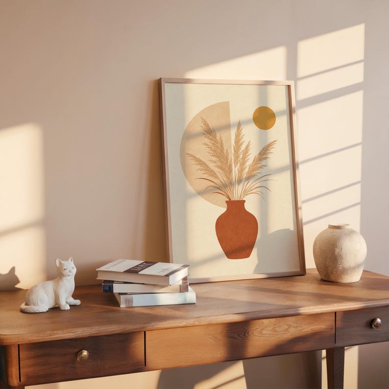Pampas grass print on dark wooden desk with stacked books and sunlight