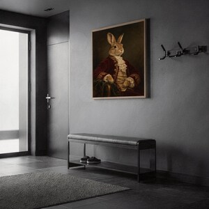 Regal rabbit portrait wall art print in a silver frame leaning against a sofa beside a decorative marble sphere.