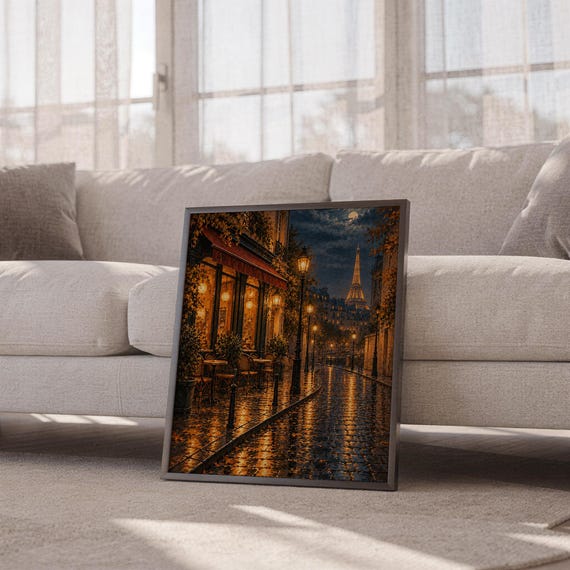 Paris eiffel tower wall art print leaning against a white sofa in a bright living room with sheer curtains.