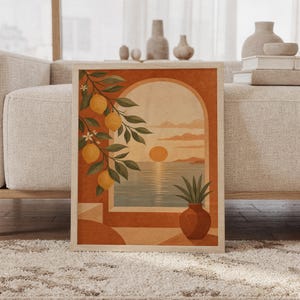 Mediterranean lemon tree wall art print of a arched window opening onto a sunset sea, framed by hanging lemons, with a rustic clay vase in terracotta, ochre and olive tones, framed and leaning against a beige sofa on a textured rug in a bright Scandinavian living room.