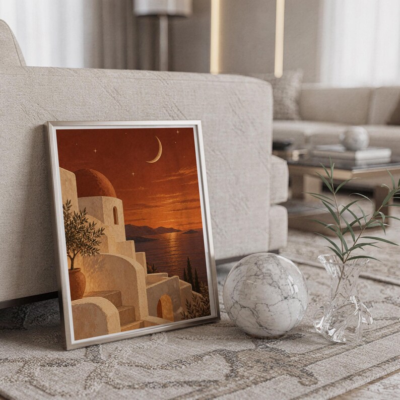 Mediterranean moonlit coastal wall art print in a silver frame leaning against a sofa beside a decorative marble sphere.