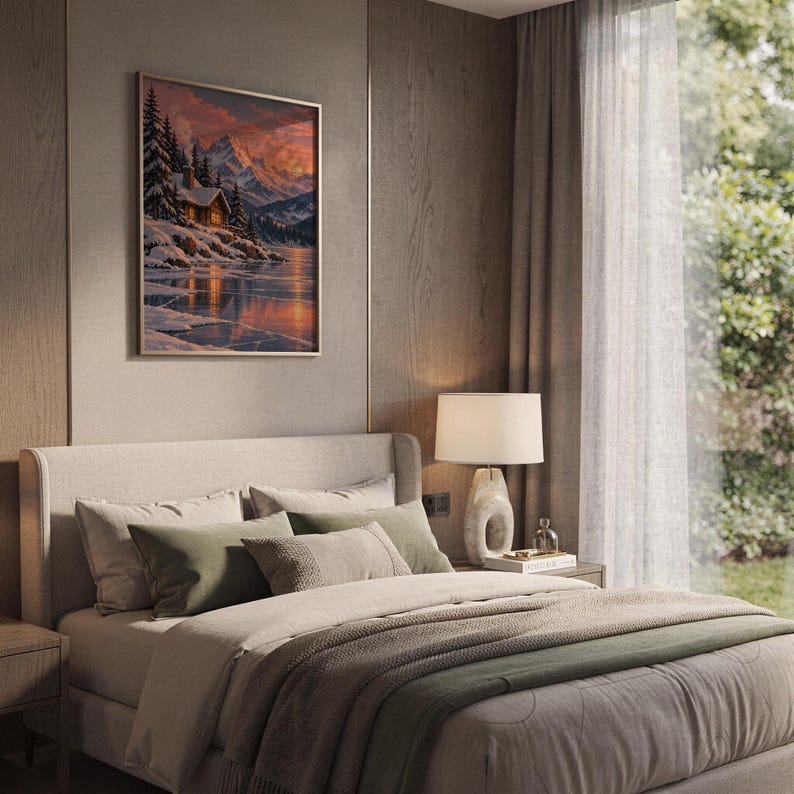 Winter cabin mountain wall art print hanging above a bed with sage green pillows in a calm neutral bedroom.
