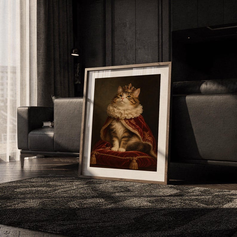 Royal cat portrait wall art print leaning on the floor beside a cream armchair next to large garden windows.