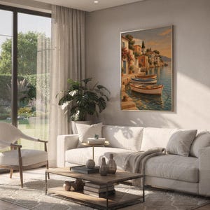 Mediterranean coastal village wall art print hanging above a white sofa in a living room with garden views.