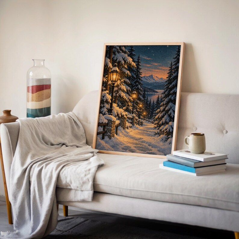 Snowy forest path wall art print leaning on a cream sofa against a beige wall beside books and a mug.