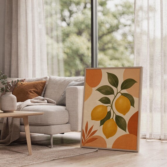Lemon branch botanical print leaning on the floor beside a cream armchair next to large garden windows.