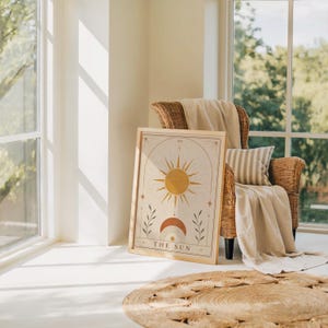 Celestial tarot card art poster leaning on floor near armchair in sunlit living room