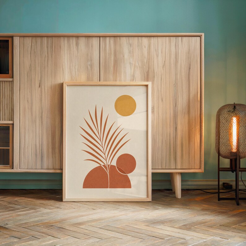 Terracotta palm leaf print leaning against light wooden sideboard cabinet