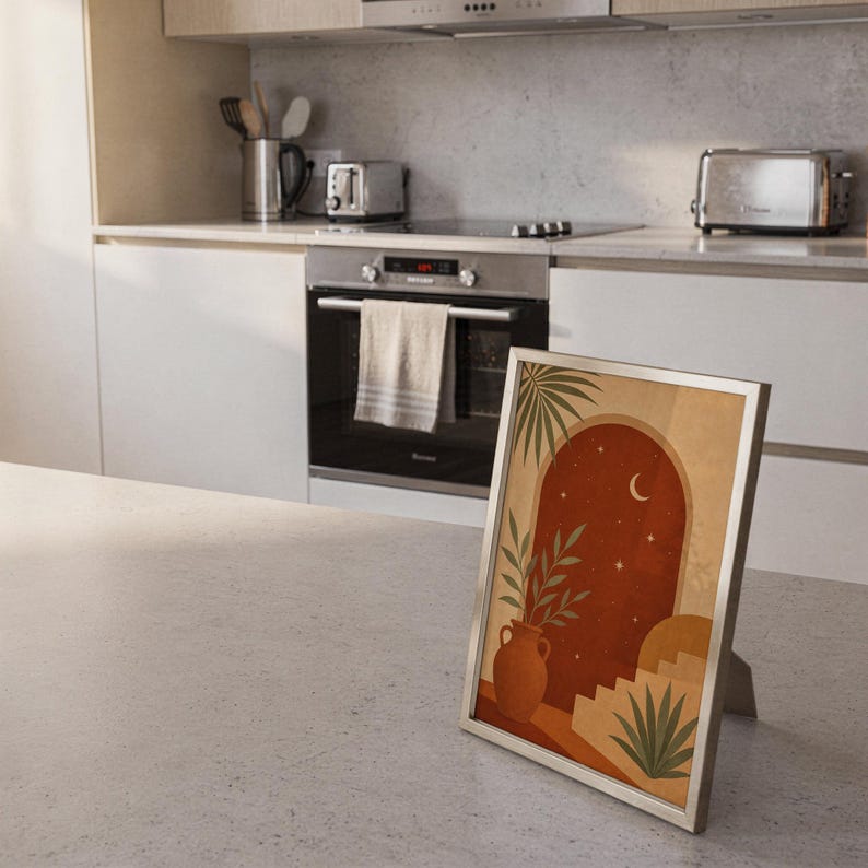 Terracotta moon and stars arch art print standing on a countertop in a modern white kitchen.