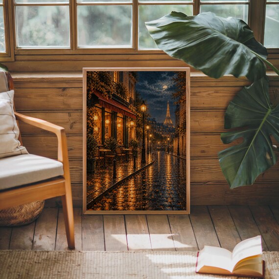 Paris eiffel tower wall art print leaning against warm wood paneling beside a wooden armchair and a monstera plant.