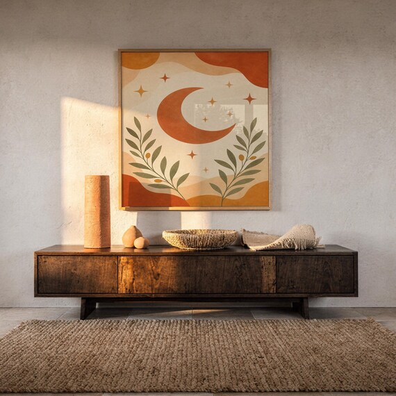 Terracotta crescent moon and olive branch print hanging above a dark wood console and jute rug in a warm neutral interior.