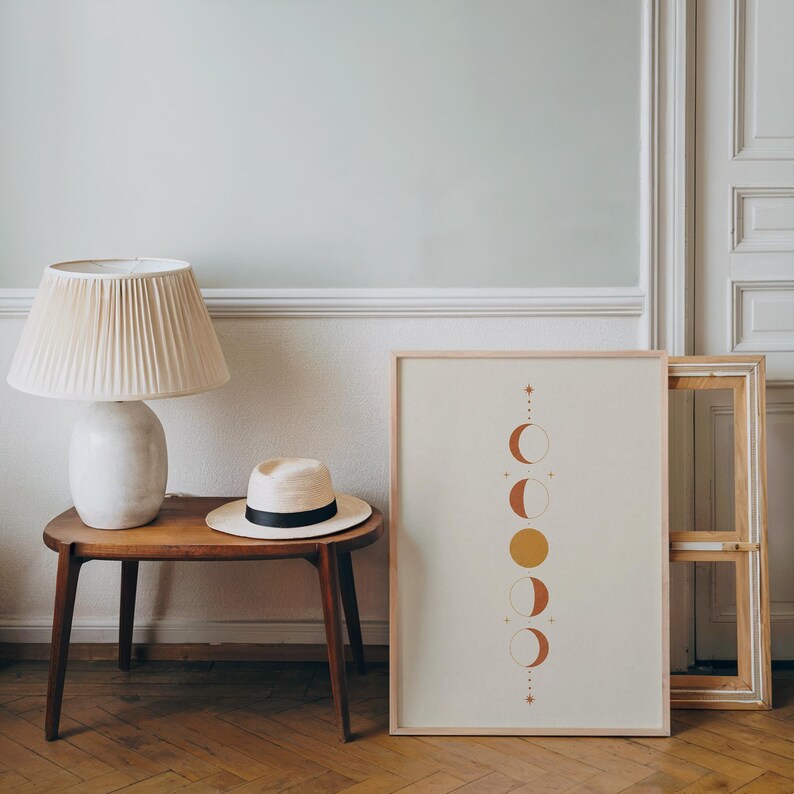 Spiritual moon phases poster resting on wooden side table in bright room