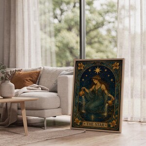The star tarot card wall art print leaning on the floor beside a cream armchair next to large garden windows.