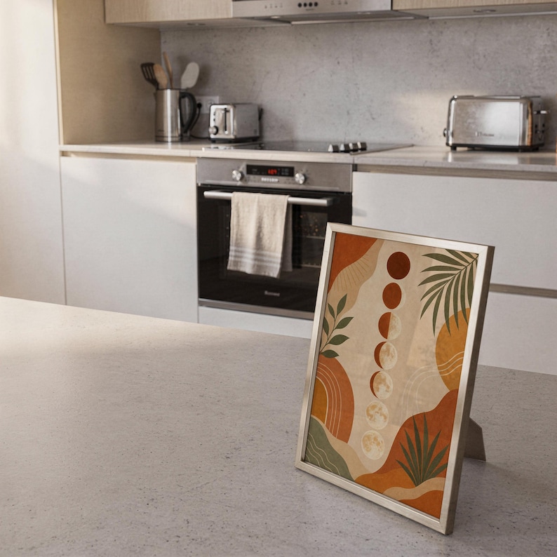 Boho moon phases art print standing on a countertop in a modern white kitchen.