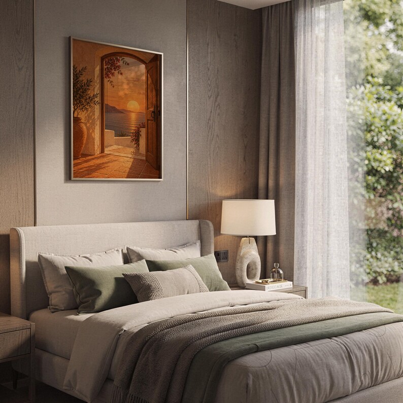 Mediterranean sunset doorway wall art print hanging above a bed with sage green pillows in a calm neutral bedroom.