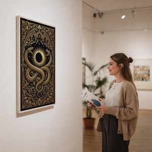 Occult snake wall art print in a silver frame leaning against a sofa beside a decorative marble sphere.