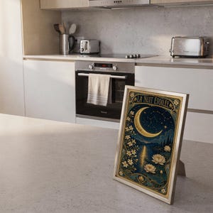 A framed vertical art print titled La Nuit Etoilee resting on a kitchen counter with stainless steel appliances in the background.
