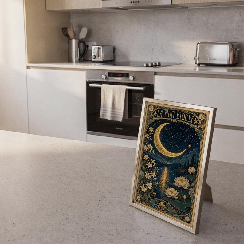A framed vertical art print titled La Nuit Etoilee resting on a kitchen counter with stainless steel appliances in the background.