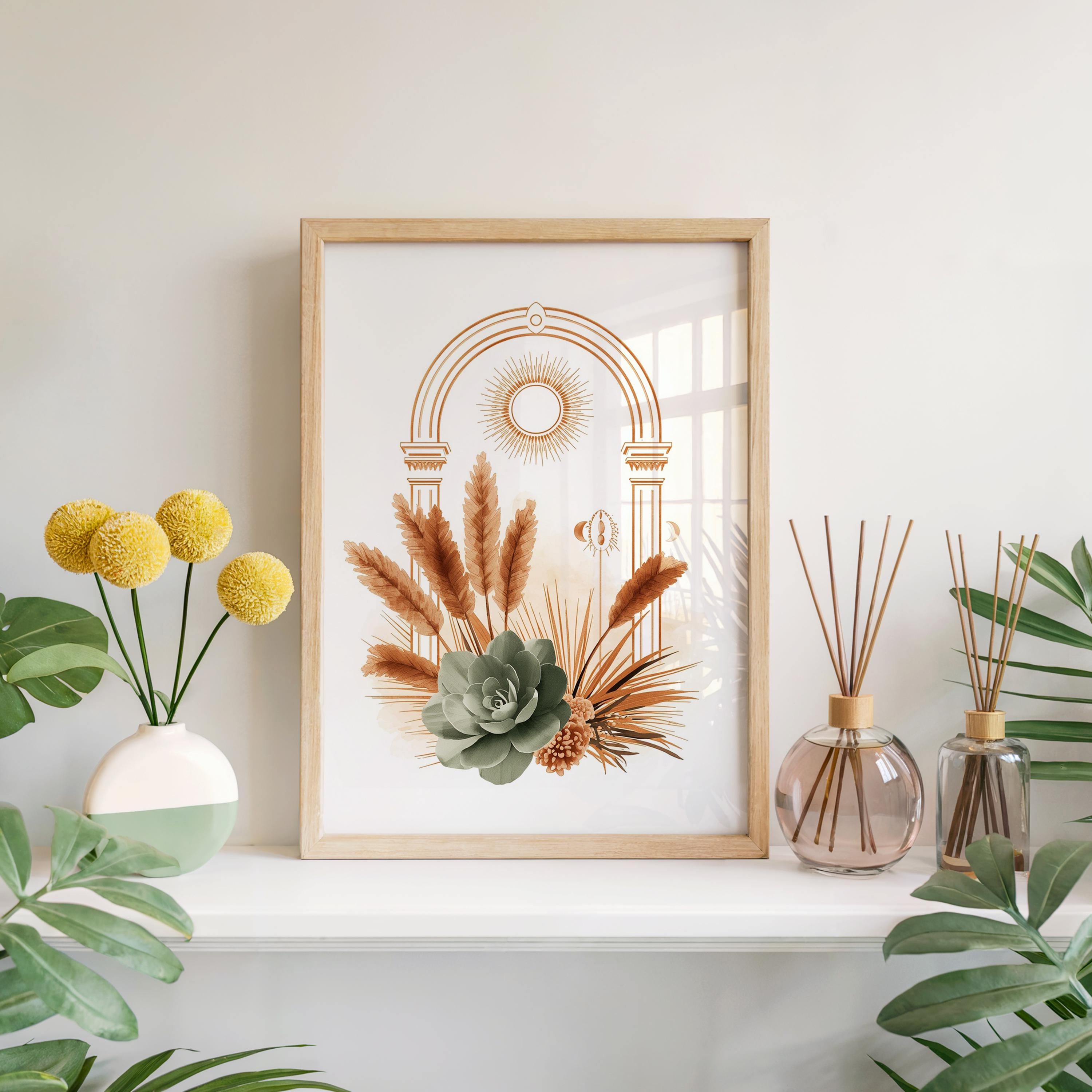 Sage green succulent botanical print framed in light wood set on a bright white fireplace mantel shelf alongside a vase of yellow flowers, glass reed diffusers, and indoor tropical houseplant leaves.