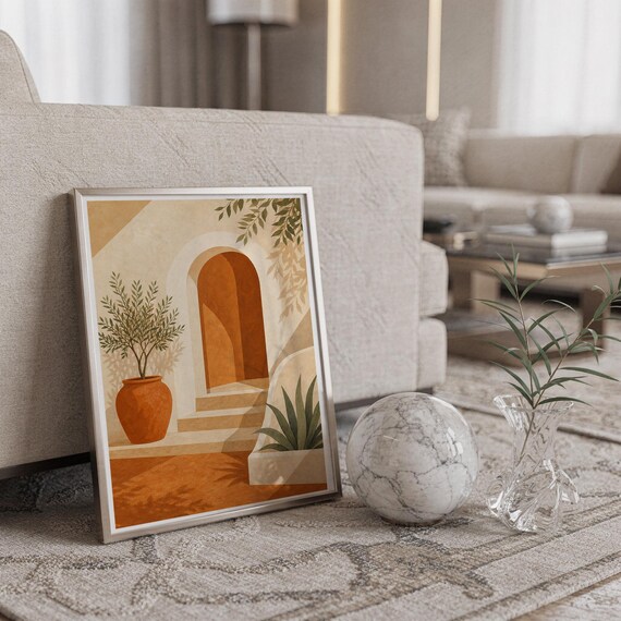 Mediterranean terracotta stairway arch print in a silver frame leaning against a sofa beside a decorative marble sphere.