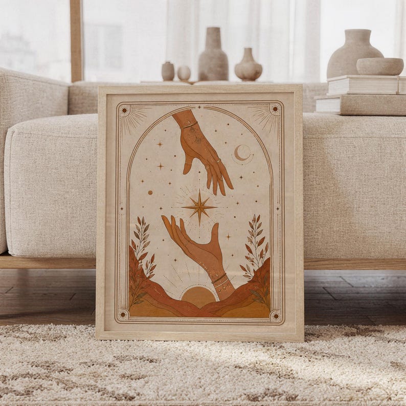 Framed mystical celestial hands tarot art print leaning on carpet in front of sofa in bright living room.