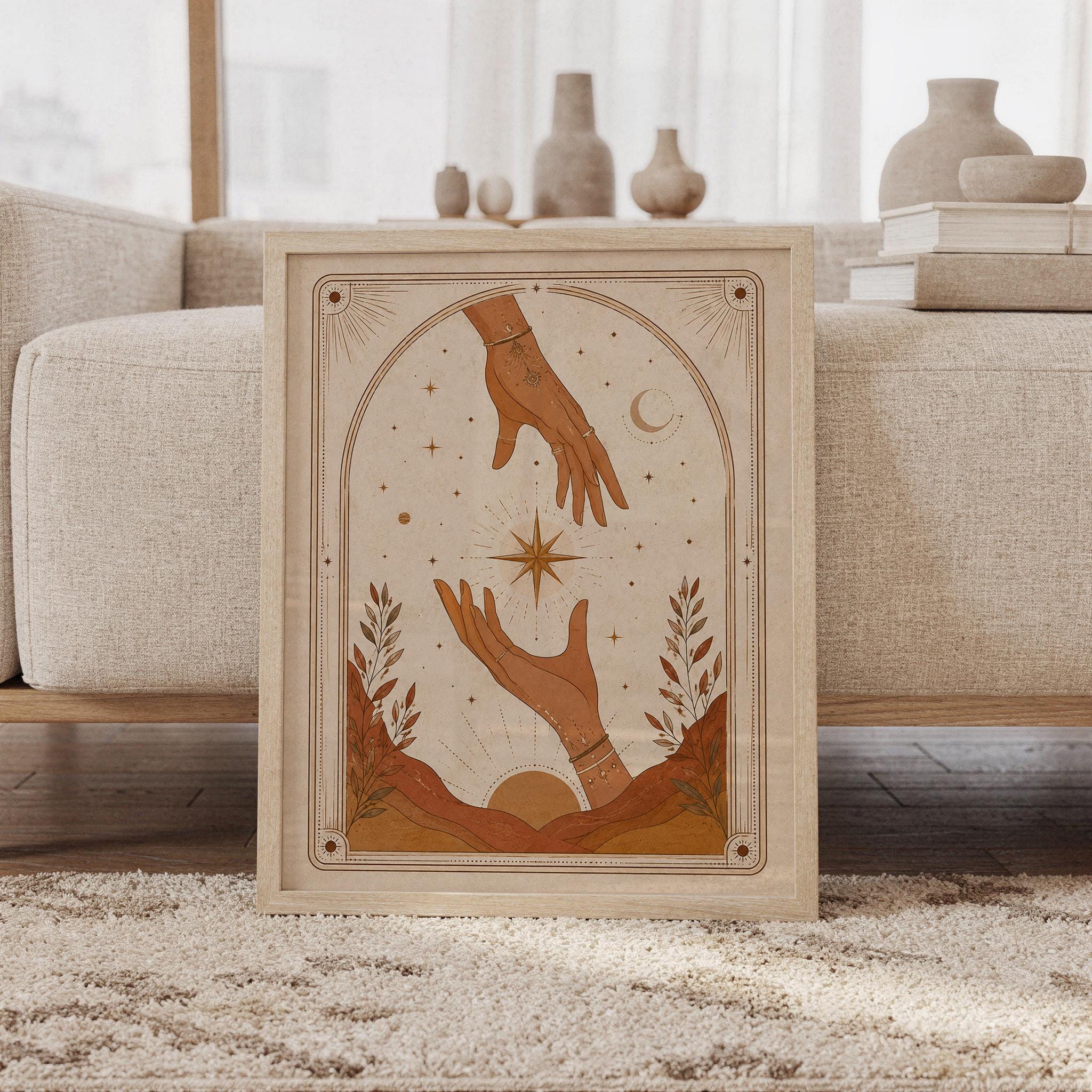 Framed mystical celestial hands tarot art print leaning on carpet in front of sofa in bright living room.