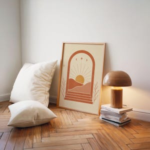Minimalist sun landscape poster leaning on wooden floor next to vintage desk lamp