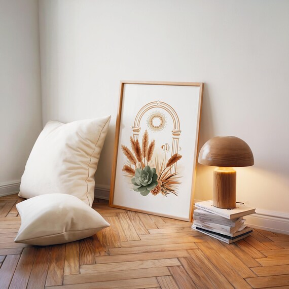 Minimalist celestial arch poster with sage green succulent and warm pampas grass leaning on hardwood floor beside a retro mushroom table lamp, soft white throw pillows, and stacked books in a cozy Japandi style bedroom corner.
