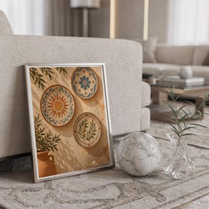 Mediterranean ceramic plate wall art print in a silver frame leaning against a sofa beside a decorative marble sphere.