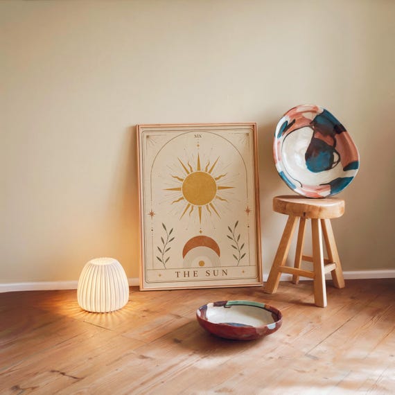 Aesthetic boho sun poster print on floor with warm floor lamp and colorful bowl