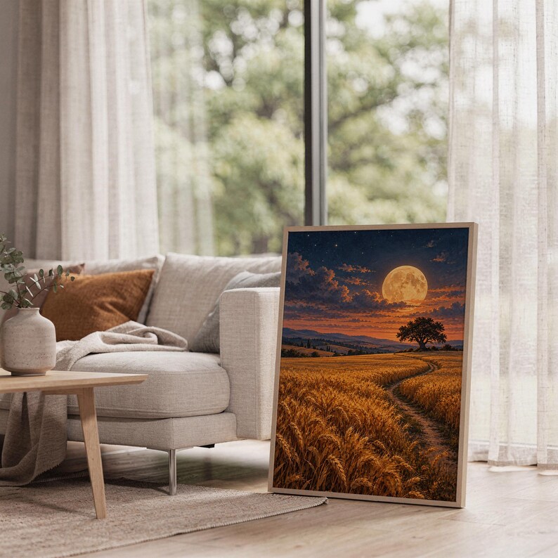 Moon wall art print leaning on the floor beside a cream armchair next to large garden windows.