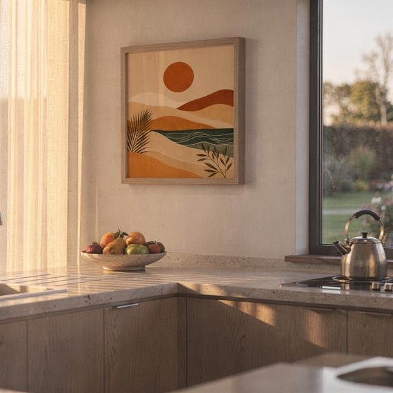 Earthy terracotta abstract landscape print framed on kitchen wall with warm natural sunset light.