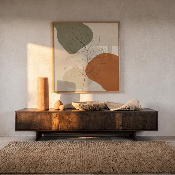 Botanical leaf art print displayed on wall over dark wooden console table