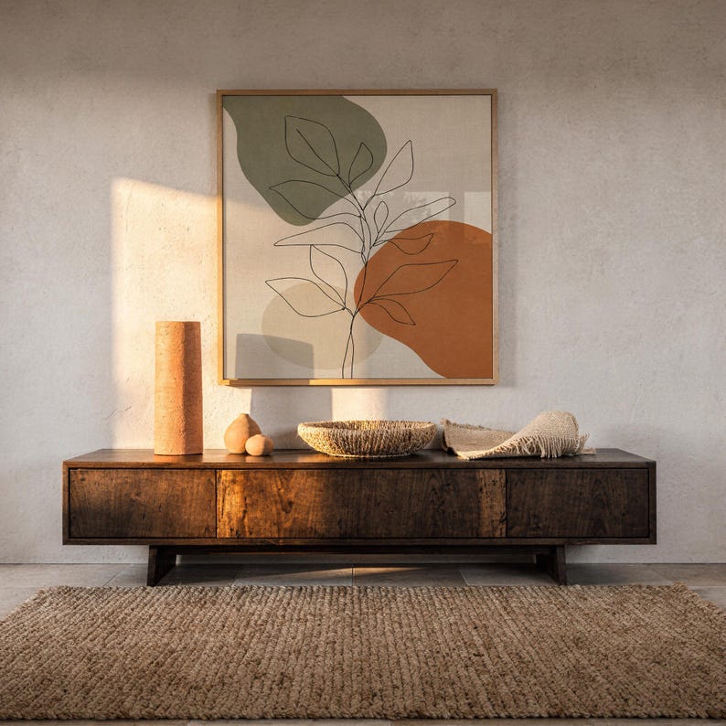 Botanical leaf art print displayed on wall over dark wooden console table