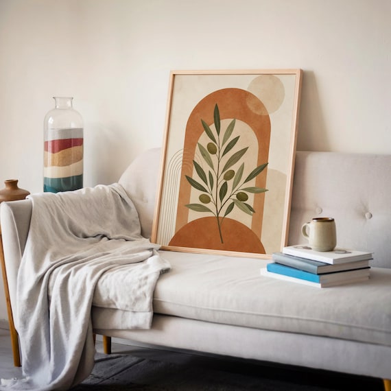 Earth tone botanical print leaning against wall on soft gray sofa