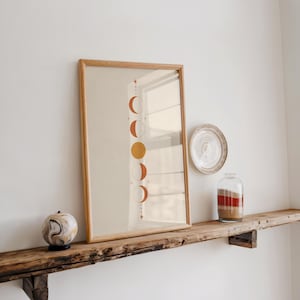 Vertical moon phases poster on rustic wooden shelf with natural lighting