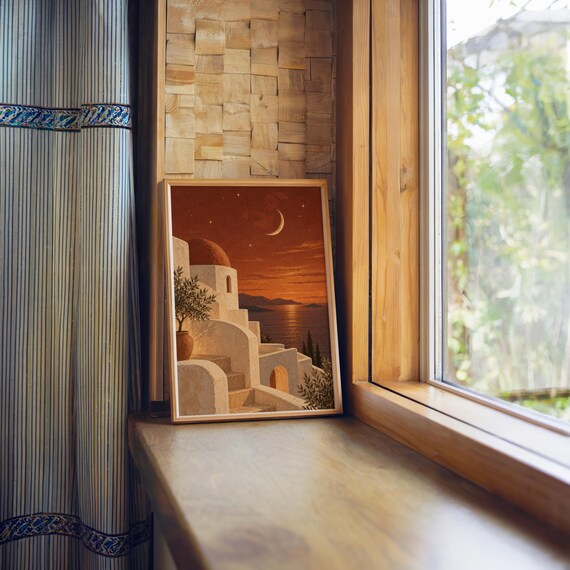 Mediterranean moonlit coastal wall art print standing on a wooden window sill in warm natural light.