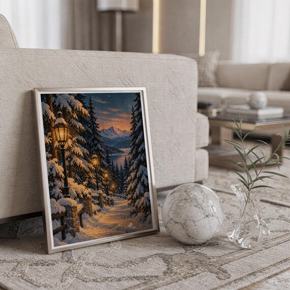 Snowy forest path wall art print in a silver frame leaning against a sofa beside a decorative marble sphere.