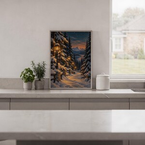 Snowy forest path wall art print standing on a white kitchen counter beside potted herbs.