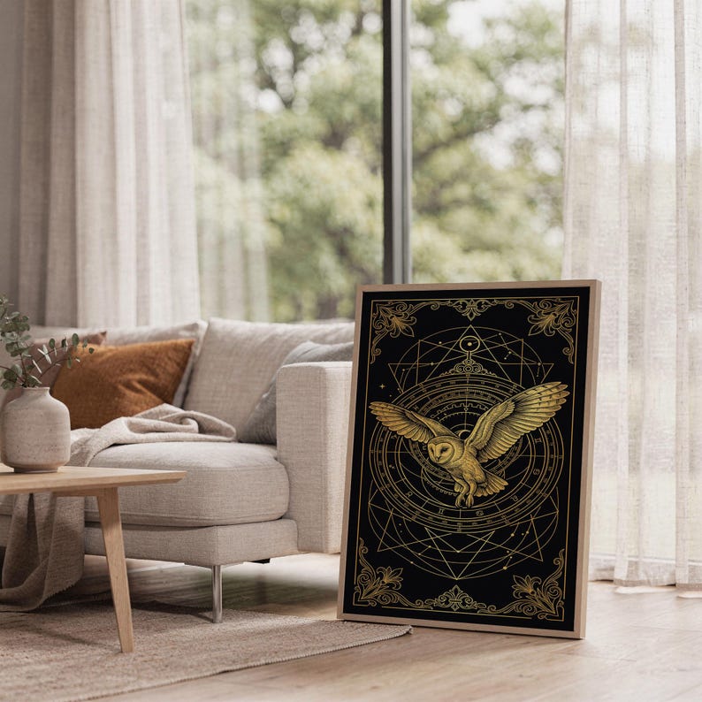 Celestial owl wall art print leaning on the floor beside a cream armchair next to large garden windows.