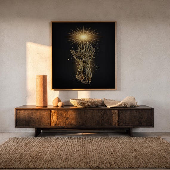 Celestial hand wall art print hanging above a dark wood console and jute rug in a warm neutral interior.