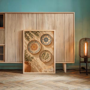 Mediterranean ceramic plate wall art print leaning against a wooden cabinet by a teal wall beside a glowing floor lamp.
