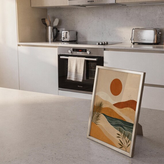 Aesthetic terracotta landscape art poster framed and leaning on a bright sunlit kitchen island counter.