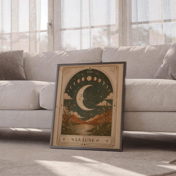 Boho celestial moon poster framed leaning against sofa in cozy sunlit living room setup.