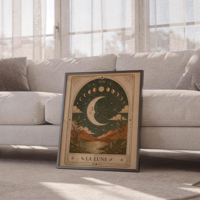 Boho celestial moon poster framed leaning against sofa in cozy sunlit living room setup.