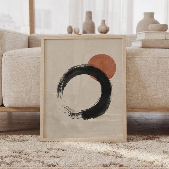 Framed Japanese Zen Enso circle poster resting on floor against sofa with ceramic decor