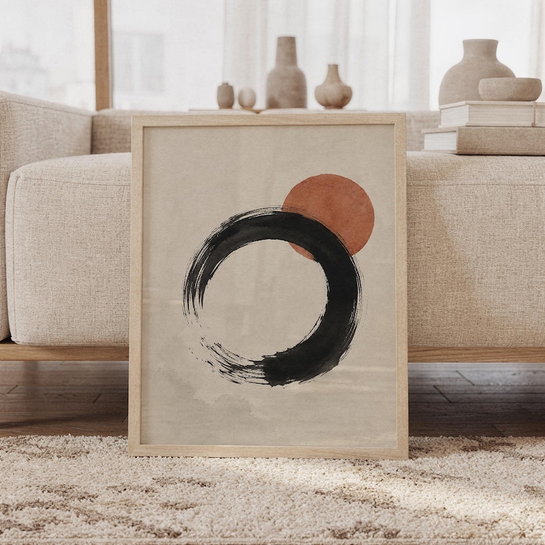 Framed Japanese Zen Enso circle poster resting on floor against sofa with ceramic decor