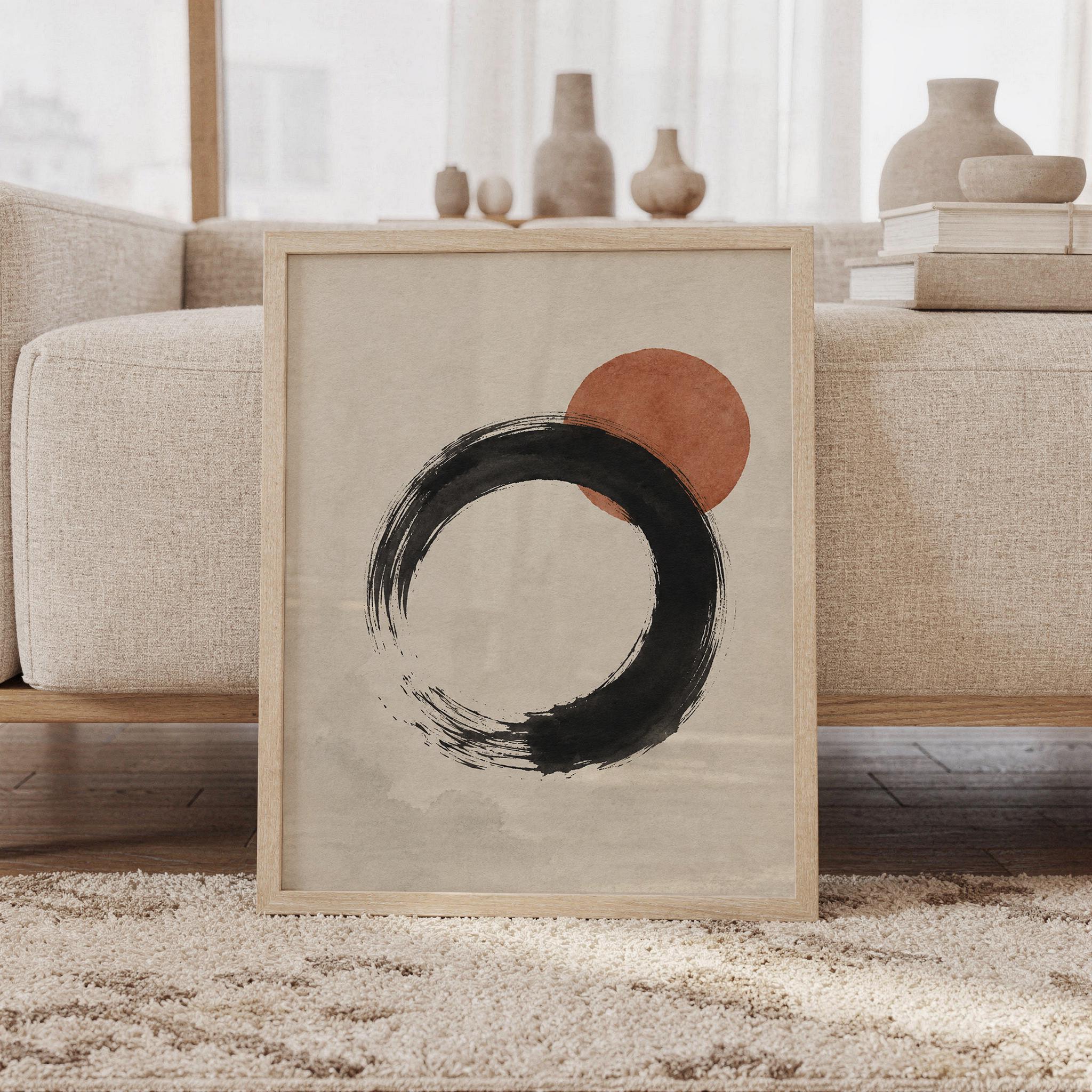 Framed Japanese Zen Enso circle poster resting on floor against sofa with ceramic decor